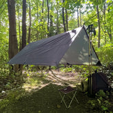 DD Tarp 2x2 set up in a forest, showcasing its compact design as a lightweight shelter by DD Hammocks.